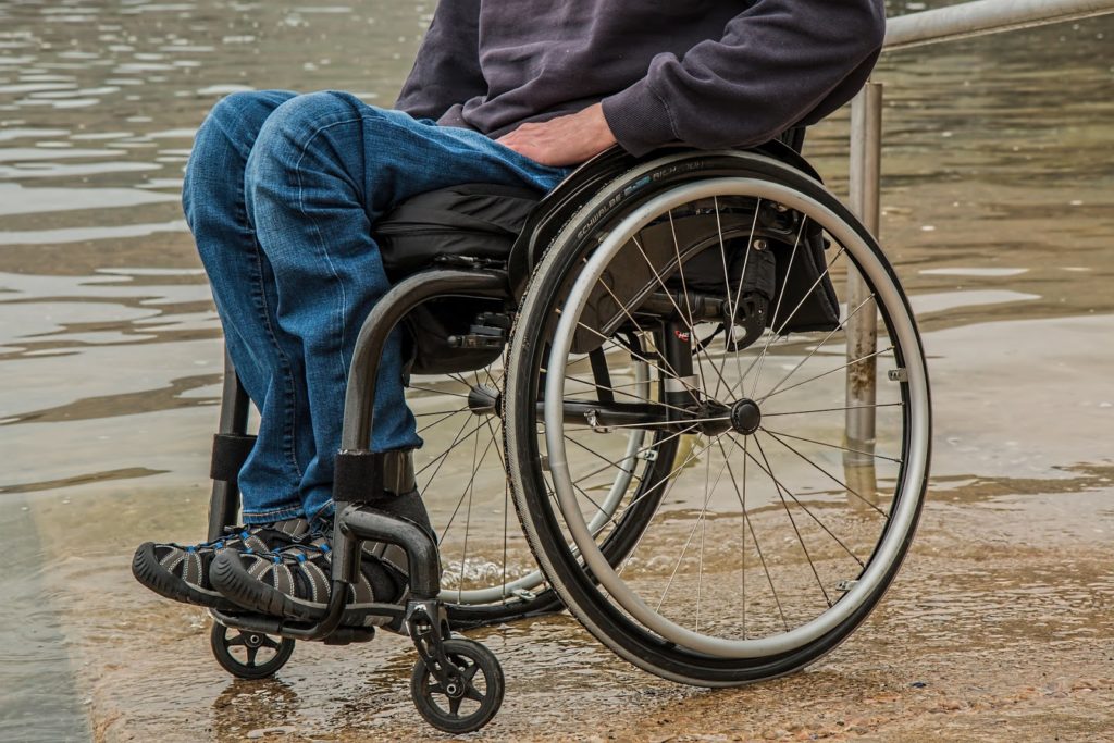 Man seated in a wheelchair shown from the waist down.