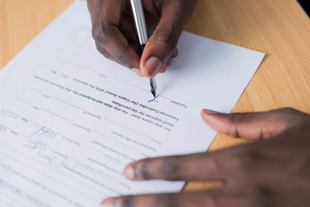 Close-up of a man's hands signing a contract.