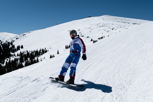 A person in a snowsuit snowboarding down a hill.