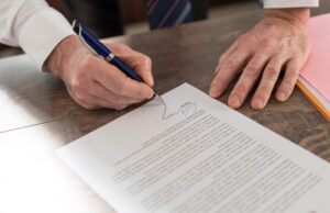 Close-up of hands signing a document.