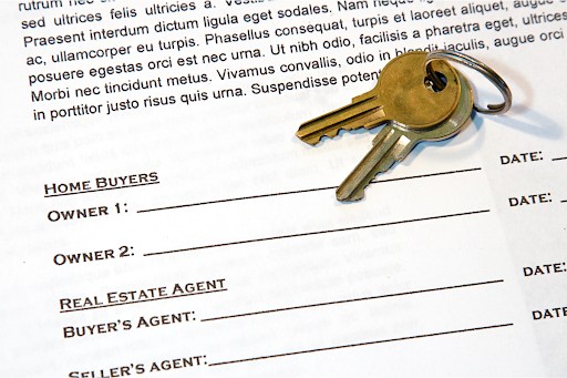 Keys lying on top of a real estate contract.