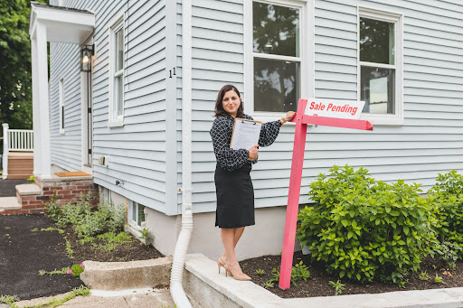 Real estate agent standing beside a "Sale Pending" sign in front of a house.